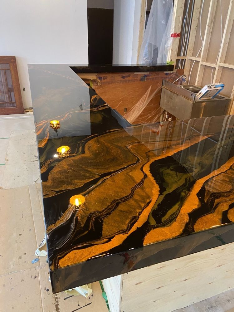 A black and gold counter top with candles on it in a room.