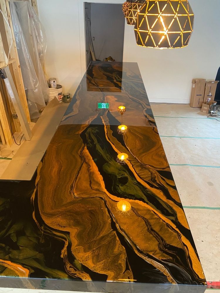A long black and gold counter top in a room with a pendant light hanging from the ceiling.