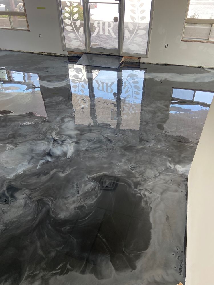 A living room with a shiny metallic floor and a reflection of a building in the floor.