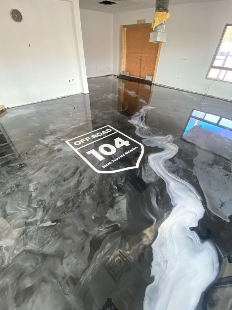 A black and white epoxy floor with a logo on it.