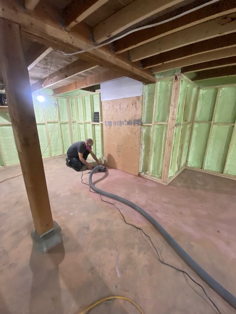 A man is using a vacuum cleaner in a basement.