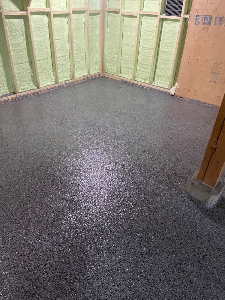 A room with a gray floor and a green wall.