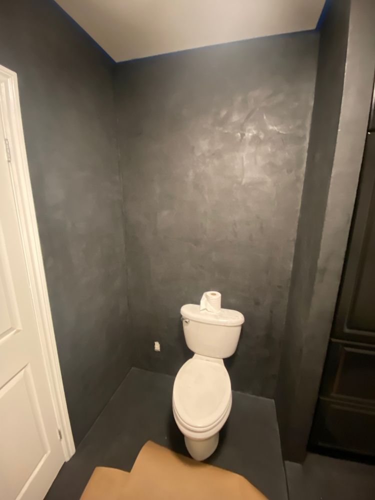 A bathroom with a toilet and a gray wall