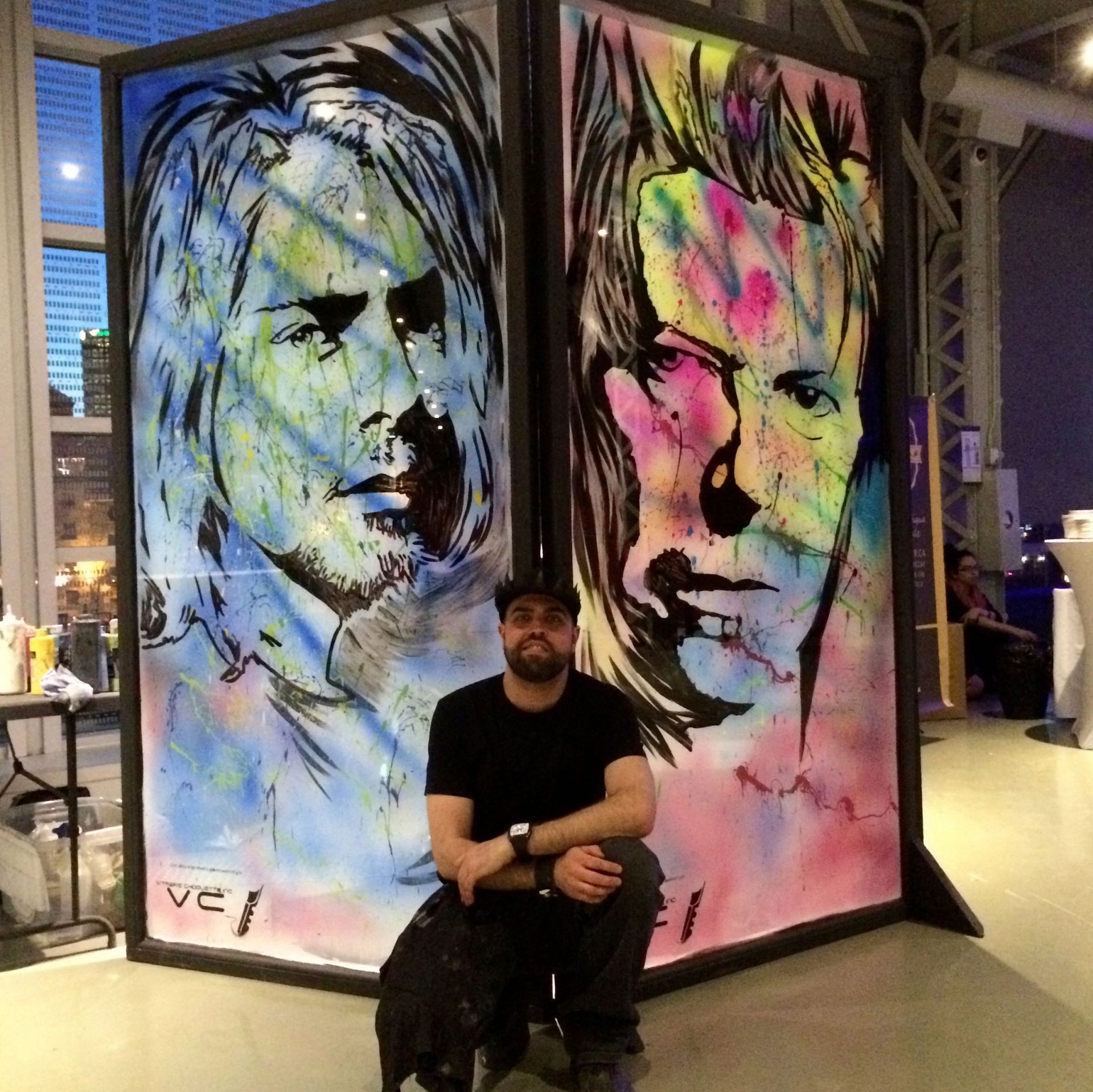 A man sitting in front of a painting that says vel