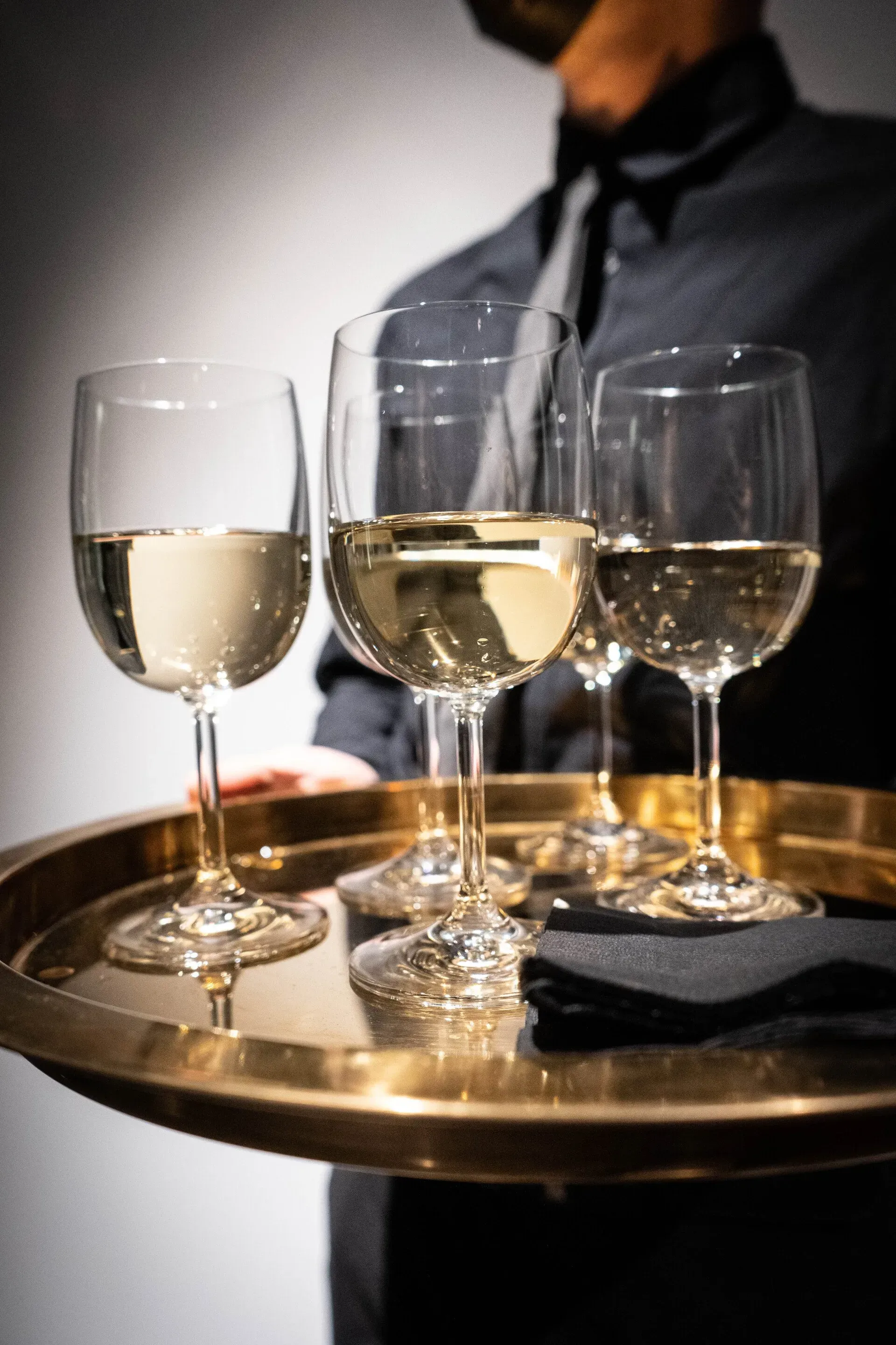 a waiter is holding a tray of wine glasses on it .