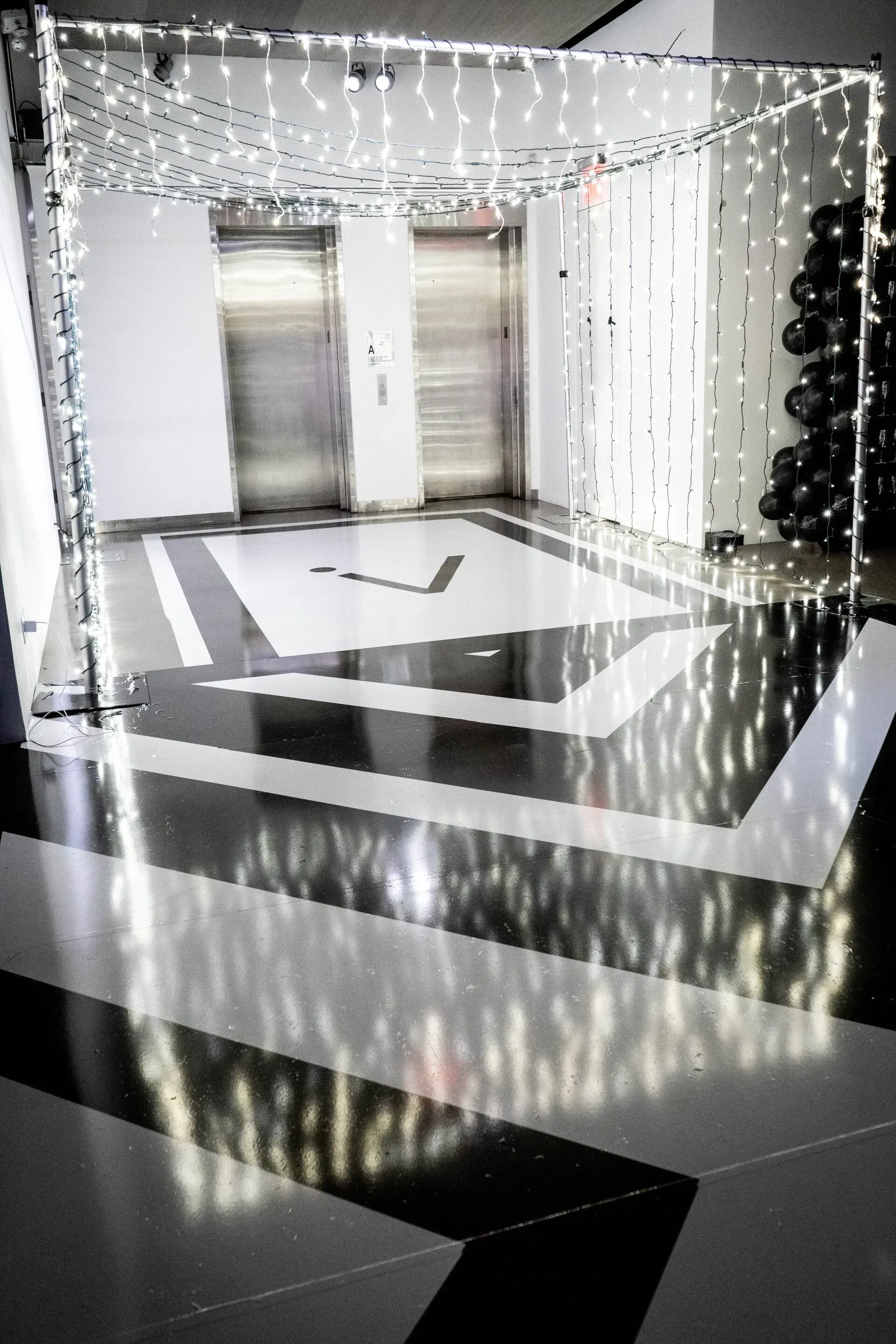 A black and white photo of a hallway decorated with christmas lights.