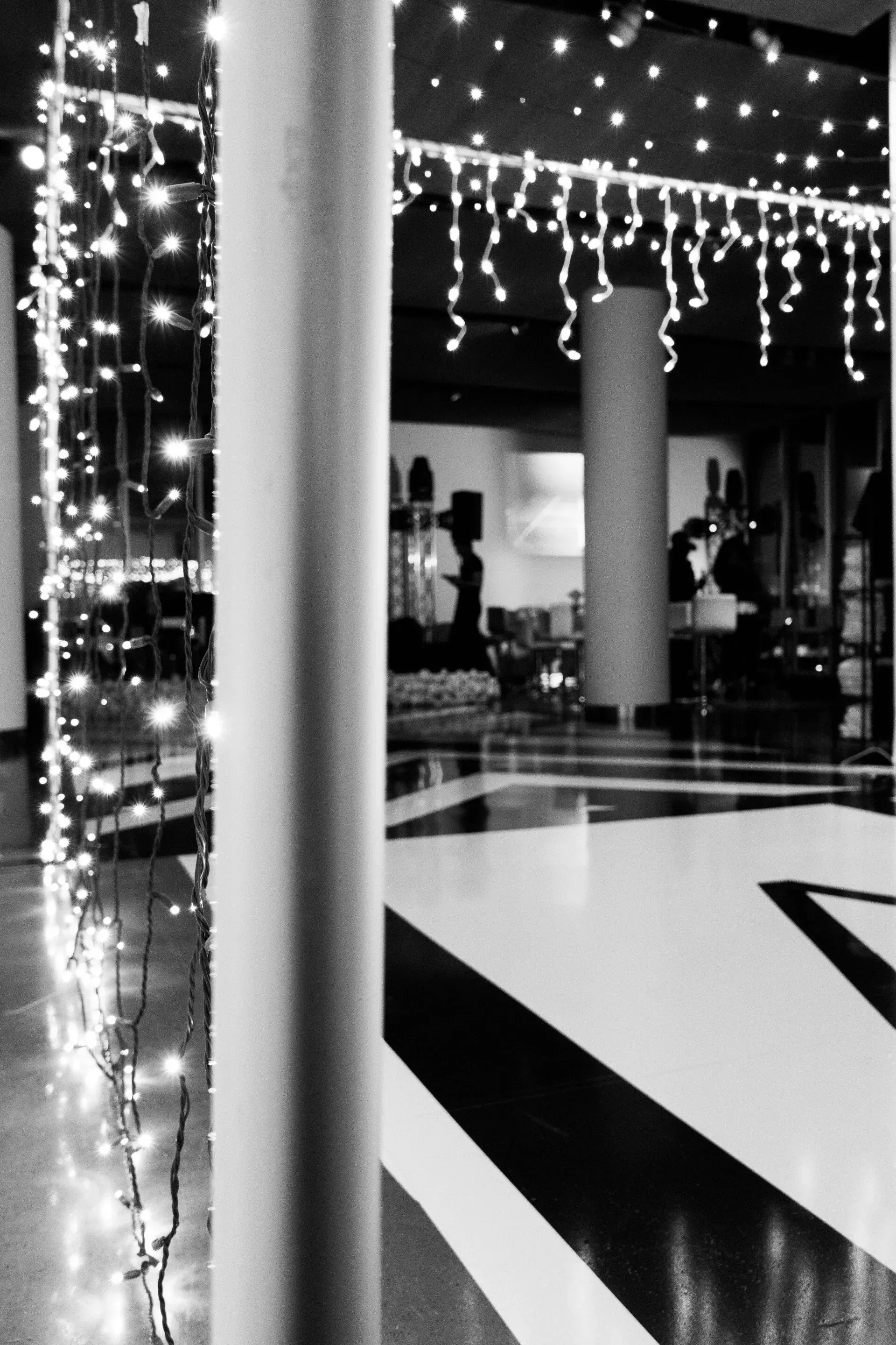 A black and white photo of a hallway with christmas lights