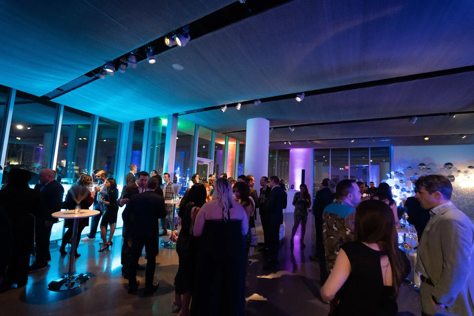 a group of people are standing in a room with blue lights on the ceiling .