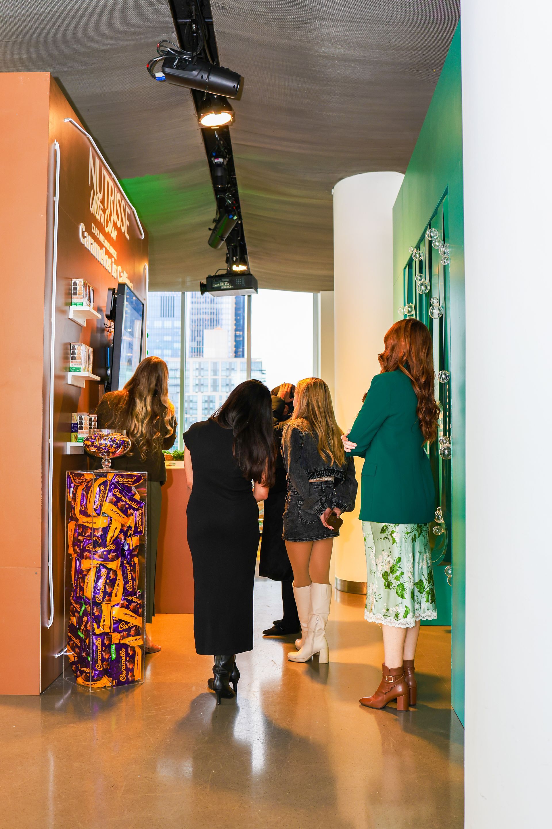 A group of women are standing in a hallway talking to each other.