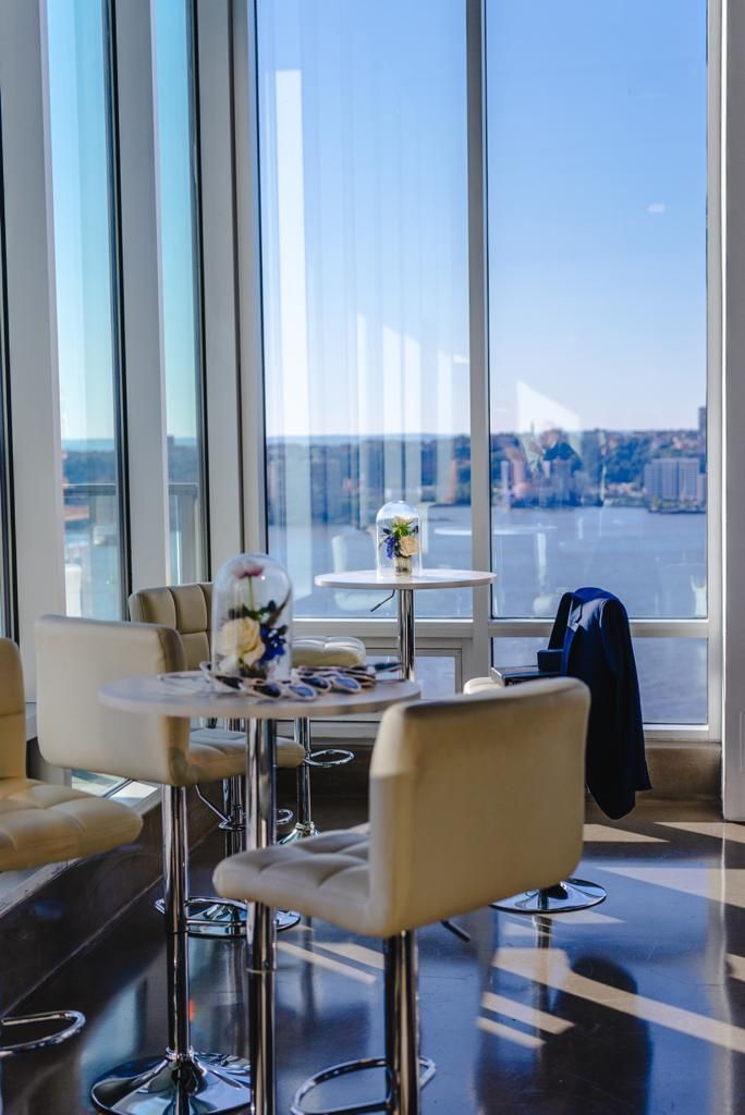 A room with tables and chairs in front of a window overlooking a body of water.