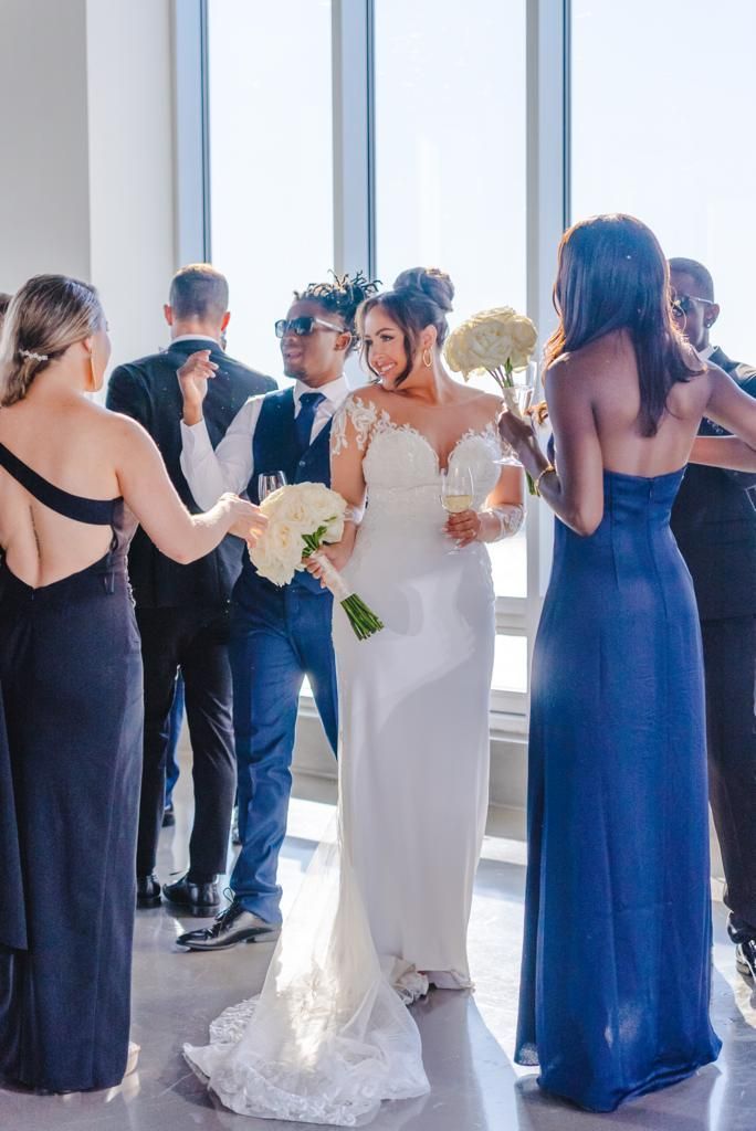 a bride and groom are standing in a room with their wedding party .