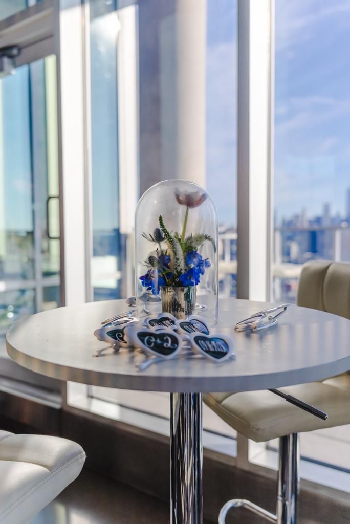 A table with a vase of flowers and sunglasses on it.