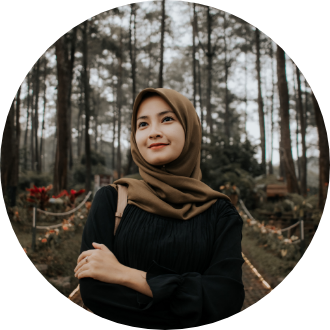 A woman wearing a hijab is standing in a forest