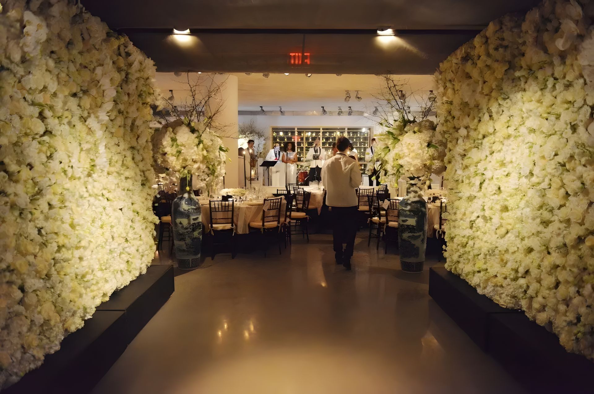 A man is walking through a hallway lined with white flowers
