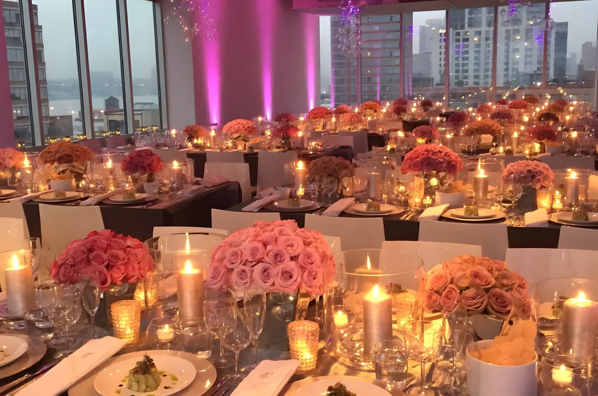 A room filled with tables and chairs decorated for a wedding reception with candles and flowers.