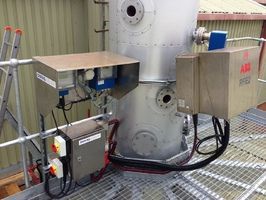 Industrial equipment with a silver tank and ABB-branded metal cabinets mounted on a grated metal platform.