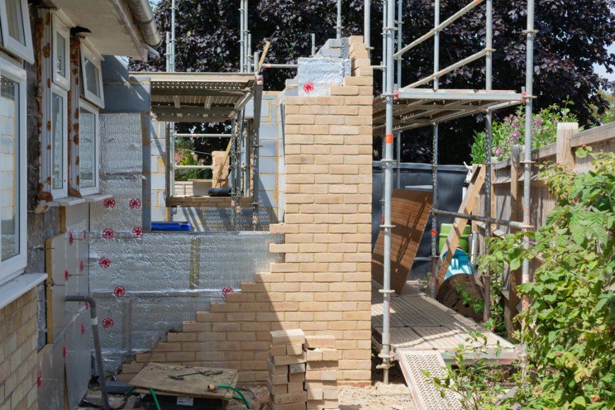 A Brick Chimney is Being Built on the Side of a House — Byron Bay Scaffold in Banora Point, NSW