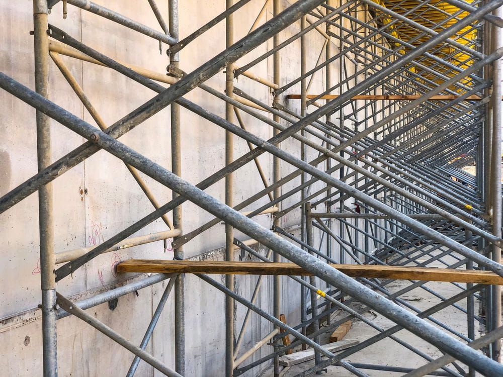 A Row of Metal Scaffolding Against a Concrete Wall on a Construction Site — Byron Bay Scaffold in Mullumbimby, NSW
