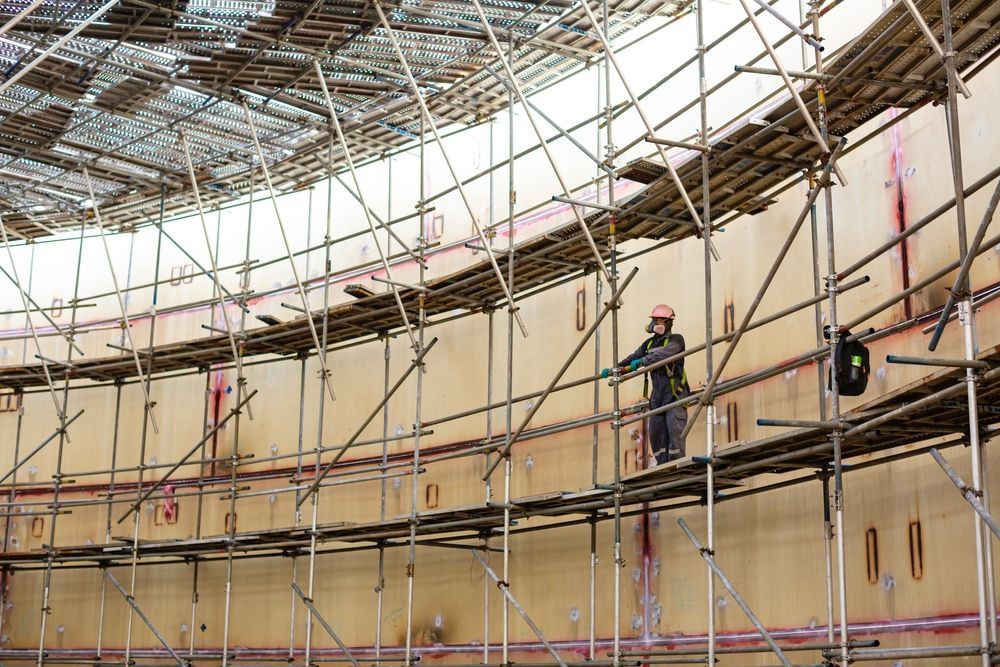A Man is Standing on a Scaffolding in a Building Under Construction — Byron Bay Scaffold in Palm Beach, QLD