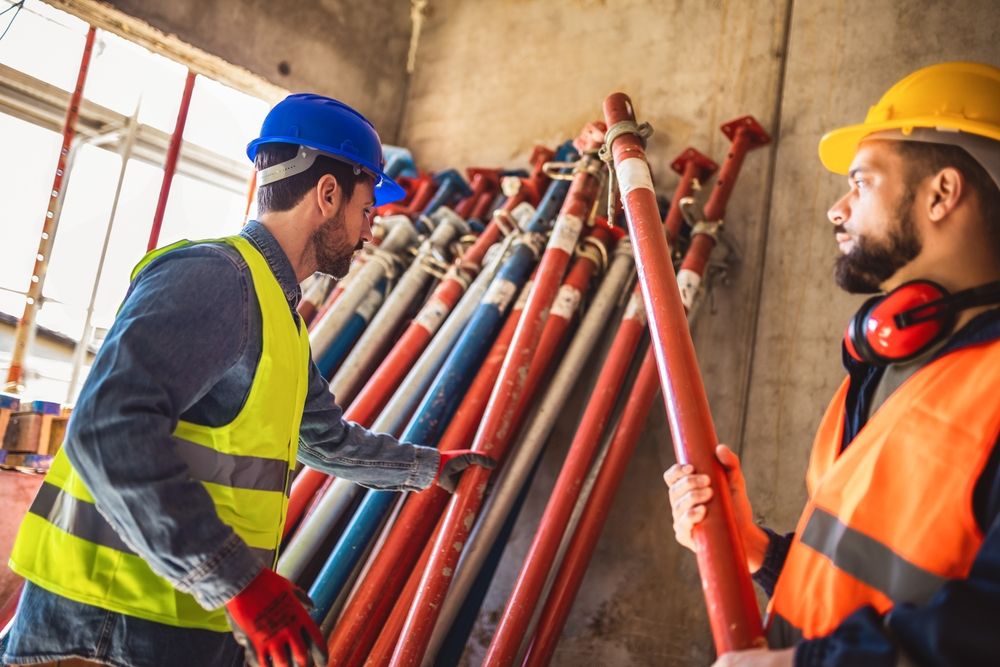 Two Construction Workers Are in Front of a Pile of Scaffolding — Byron Bay Scaffold in Cabarita Beach, NSW