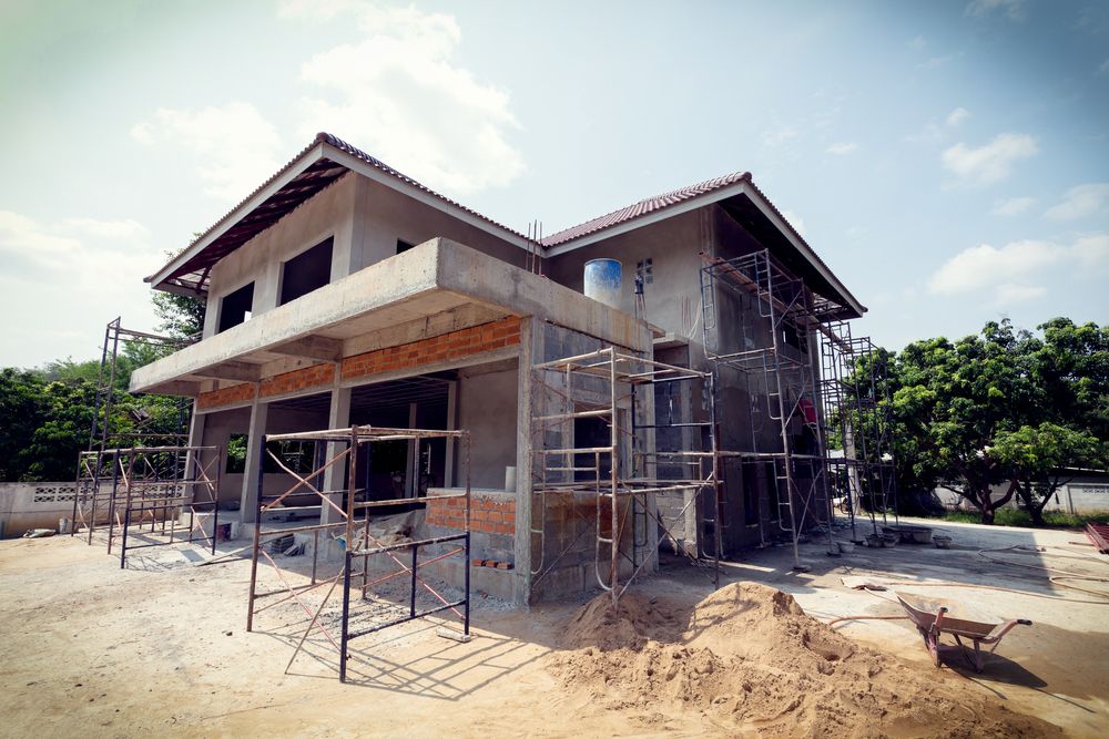 A House is Being Built With Scaffolding and a Wheelbarrow in Front of It — Byron Bay Scaffold in Evans Head, NSW