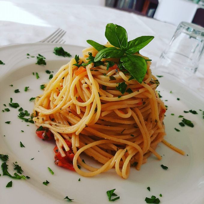 Spaghetti al sugo di pomodoro guarniti con basilico su un piatto bianco