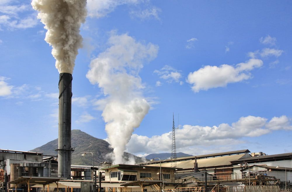 Smoke is Coming Out of a Chimney at a Factory — Optimum Pest Services In Gordonvale, QLD