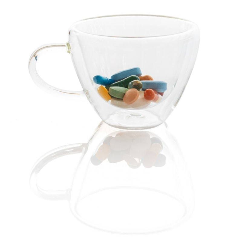 A clear glass cup with pills inside of it