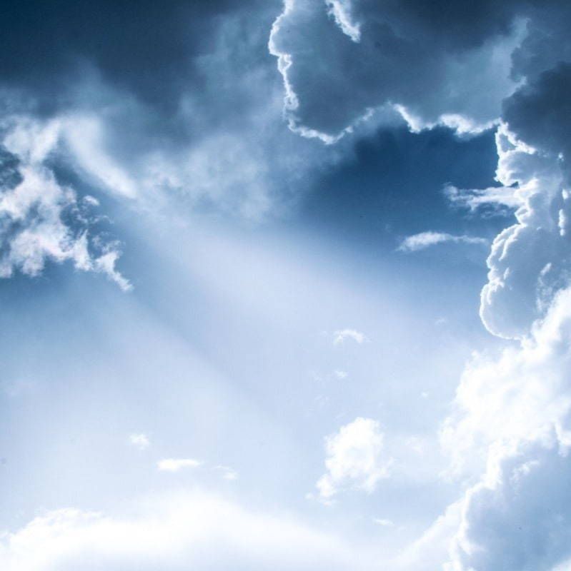 The sun is shining through the clouds in the sky