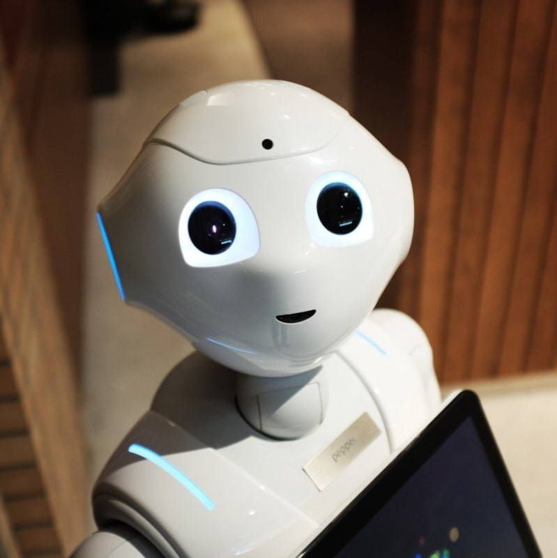 A white robot is holding a tablet and looking at the camera