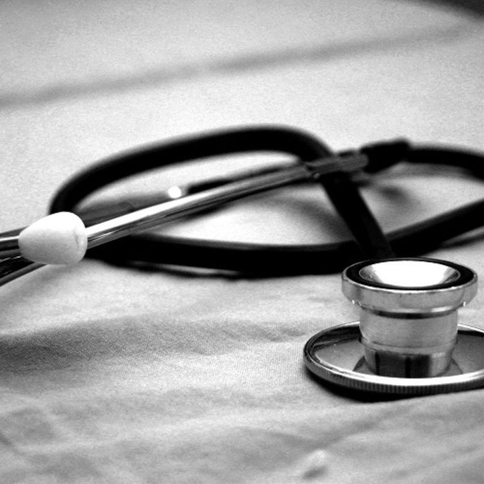 A black and white photo of a stethoscope on a table.