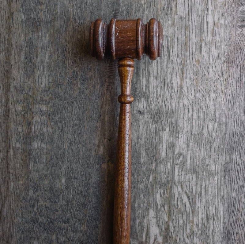 A wooden judge 's gavel is sitting on a wooden table.