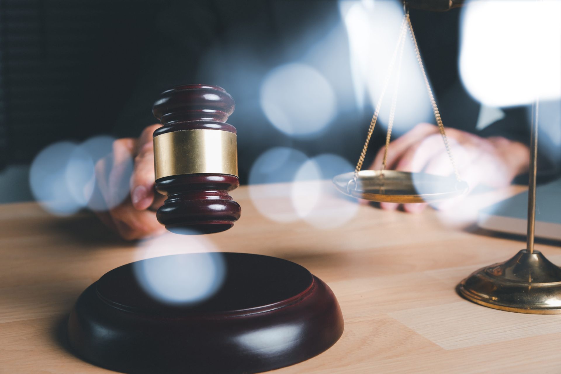 Gavel and judge’s hammer on a desk with a blurred courtroom background and scales of justice