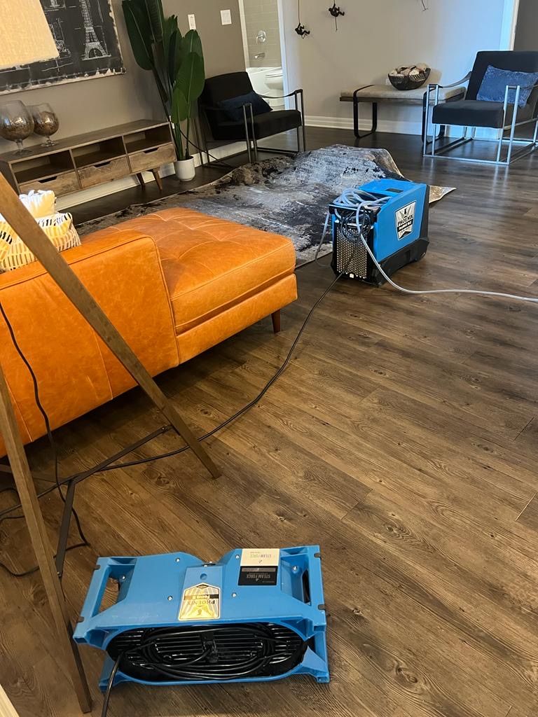 A living room with a couch , chairs , and a fan on the floor.