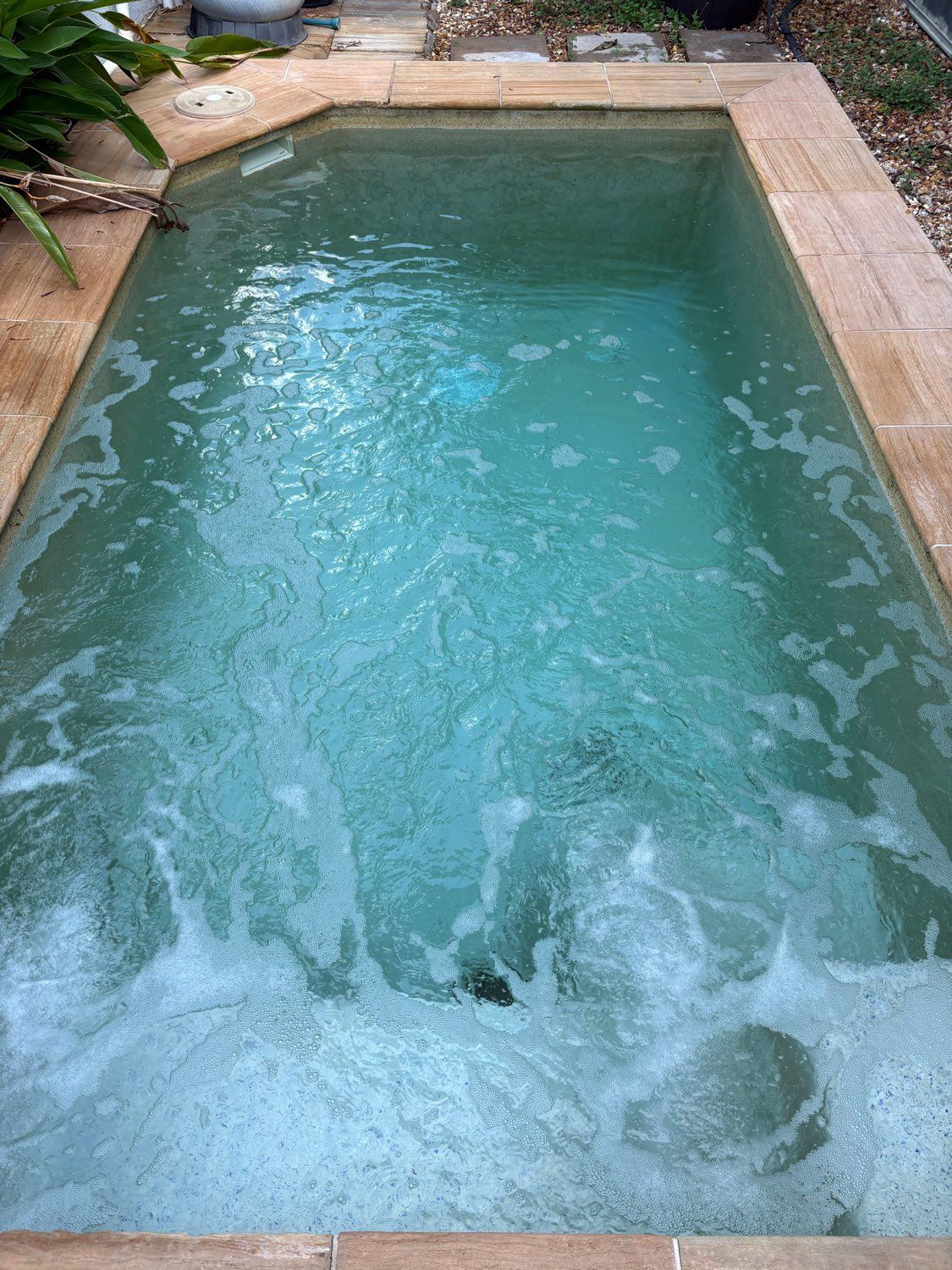 A small, rectangular swimming pool with churning, turquoise water, surrounded by light brown stone coping — Friendly Pool & Spa Care in Coconut Grove, NT