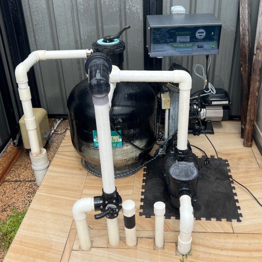 Pool filtration system with a large black sand filter, pump, and control panel on a paved outdoor area — Friendly Pool & Spa Care in Palmerston, NT