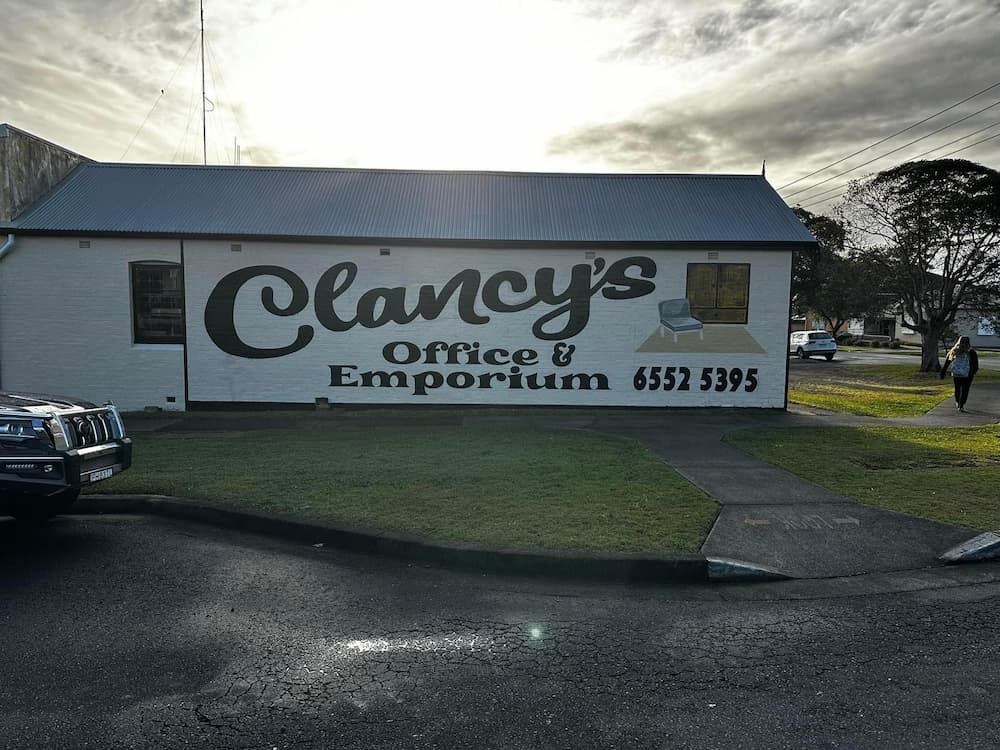 Two People Pose in Front of Clancy's Office & Emporium — Clancy's Office And Emporium in Taree, NSW