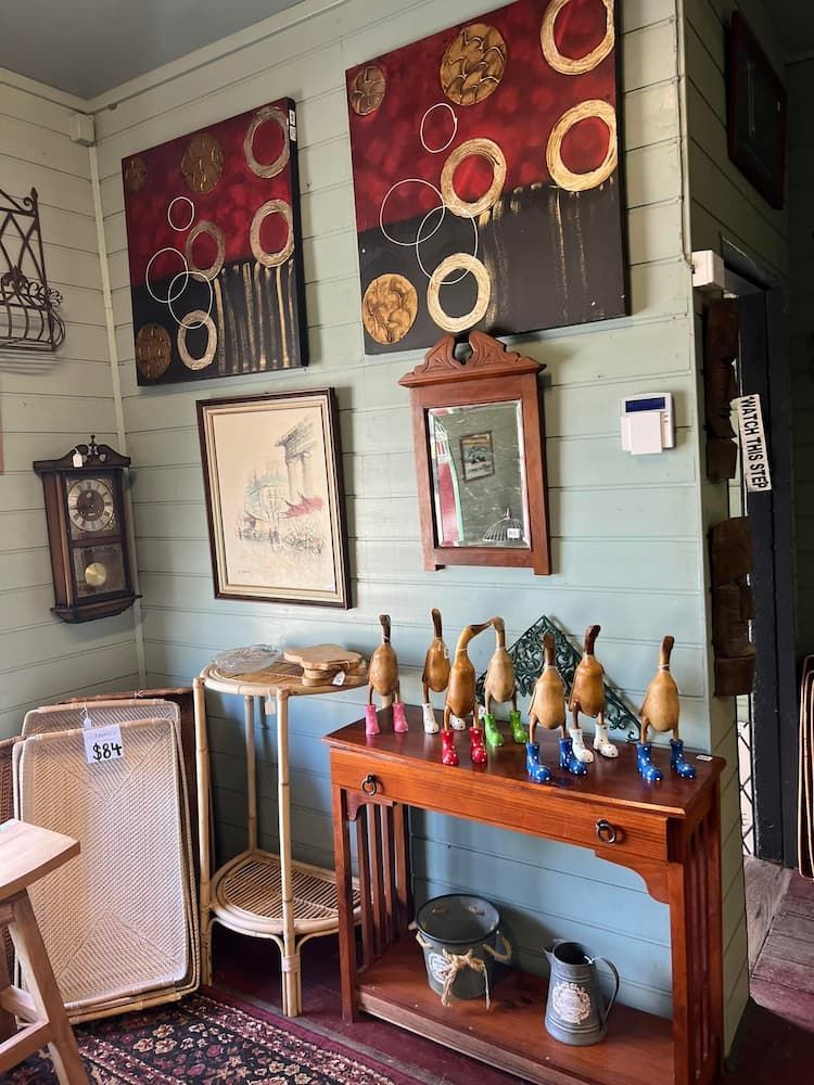 An antique shop interior with paintings, wooden figurines, and various other items — Clancy's Office And Emporium in Taree, NSW
