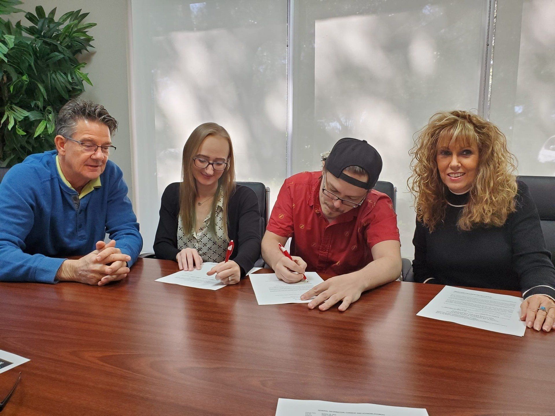 A group of people are sitting at a table signing papers.