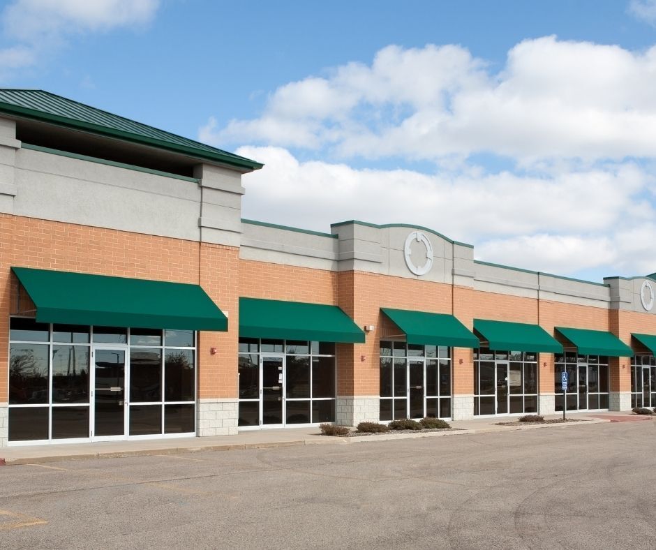 A brick building with green awnings on the windows