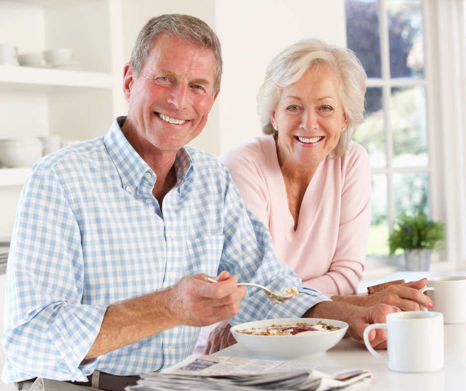 A man and a woman are sitting at a table eating cereal.