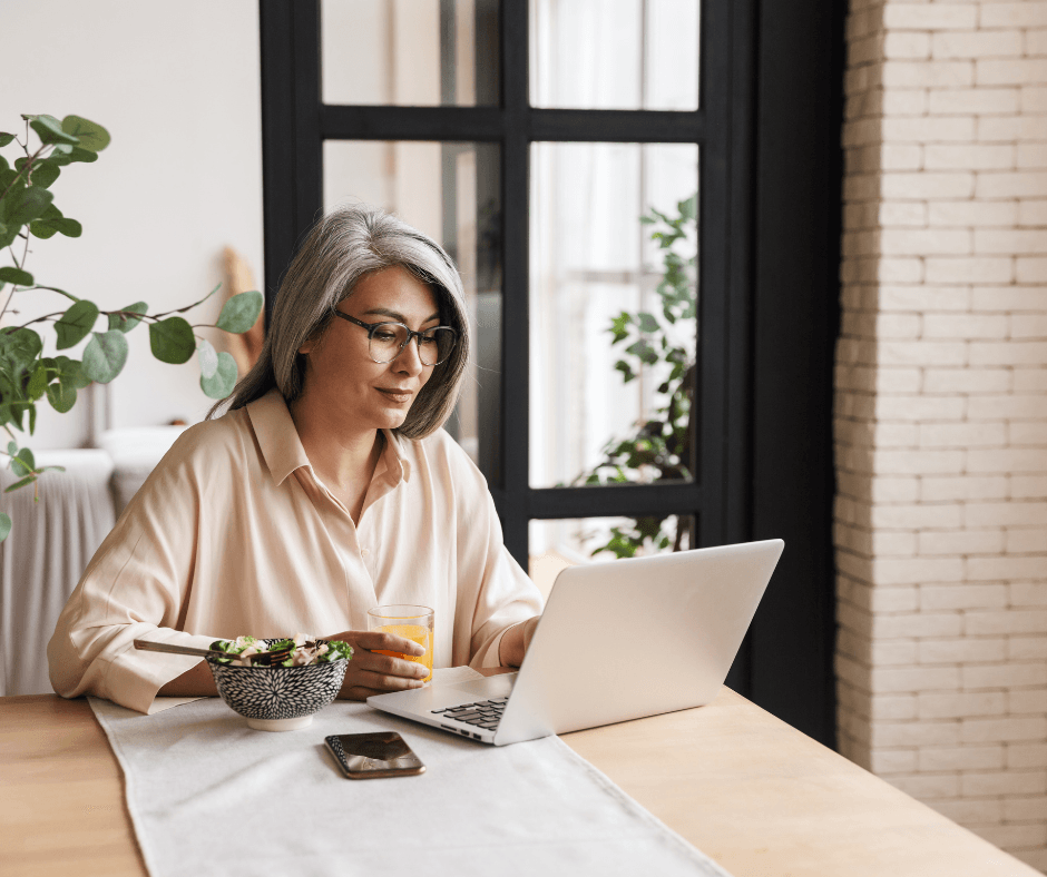 A woman is sitting at a table using a laptop computer.