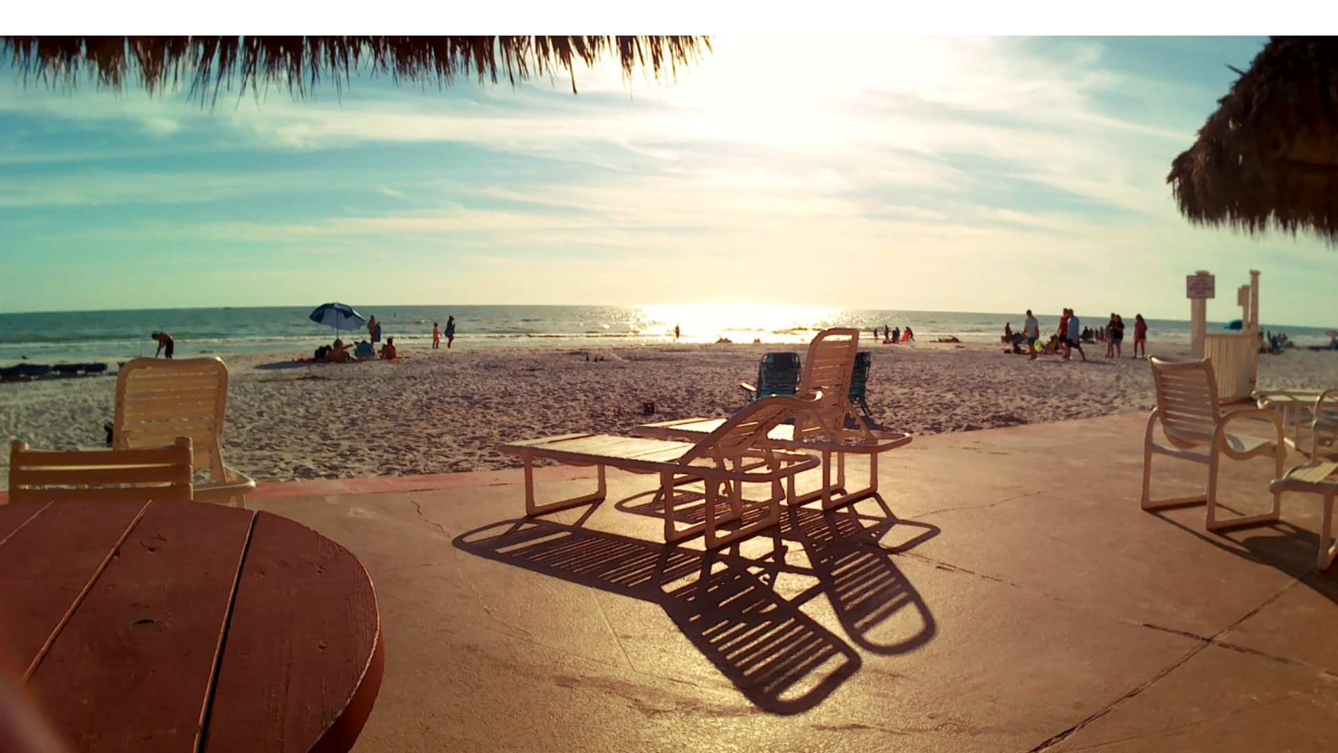A table and chairs on a beach with a sunset in the background