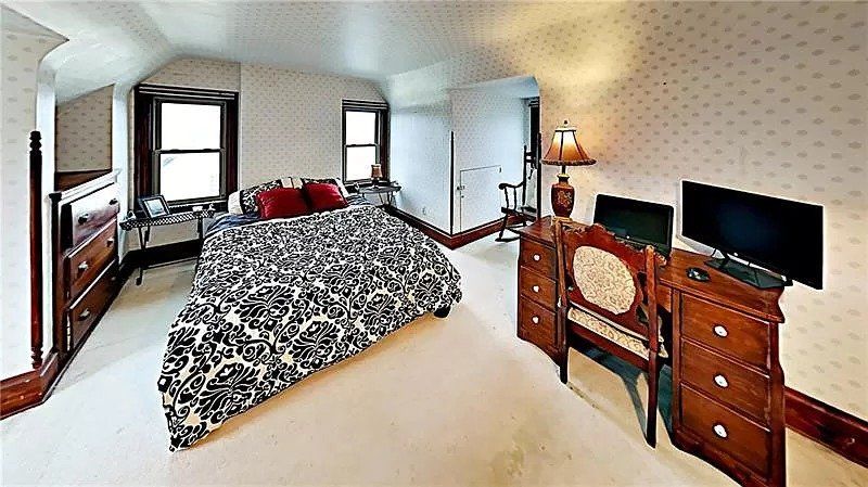 A bedroom with a king size bed , dresser , desk and television.