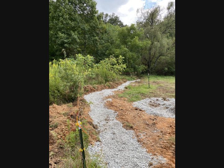A gravel path going through a field with trees in the background