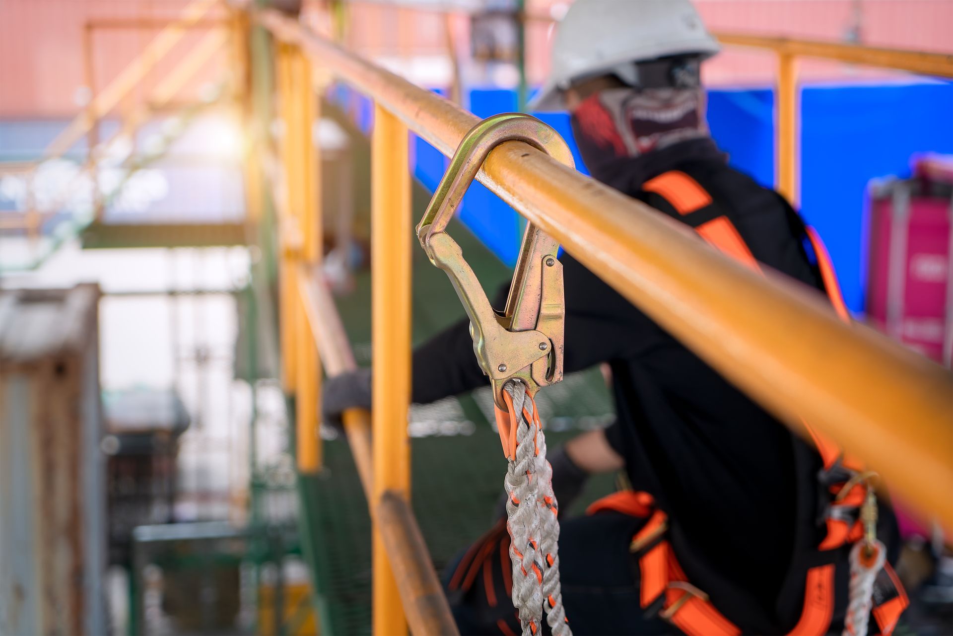 Closeup of a safety harness with a blurred construction worker behind it with more safety gear.