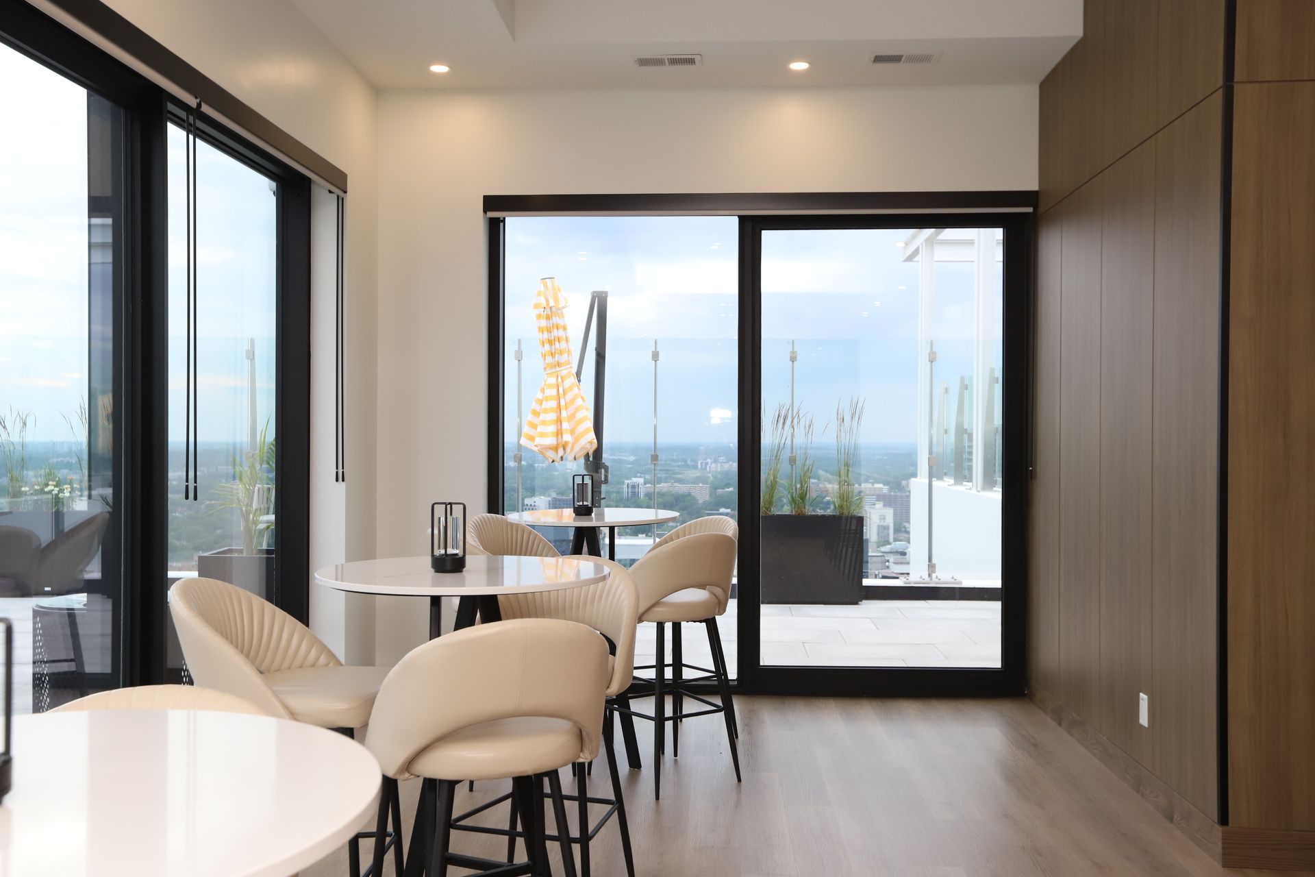 Interior dining area with tables, chairs, and floor-to-ceiling windows. City view.