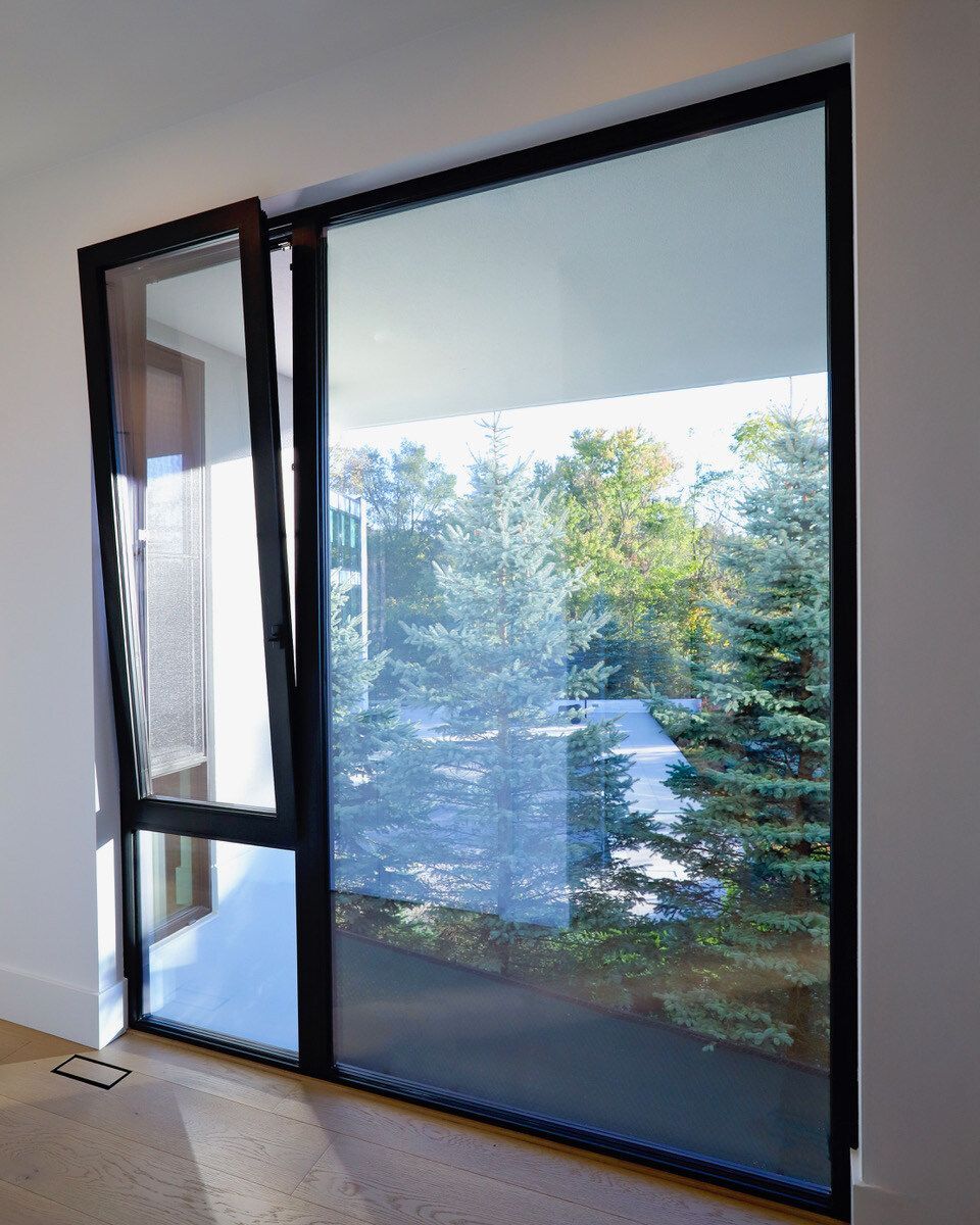 Black-framed window, partially open, showing a view of trees and a balcony.