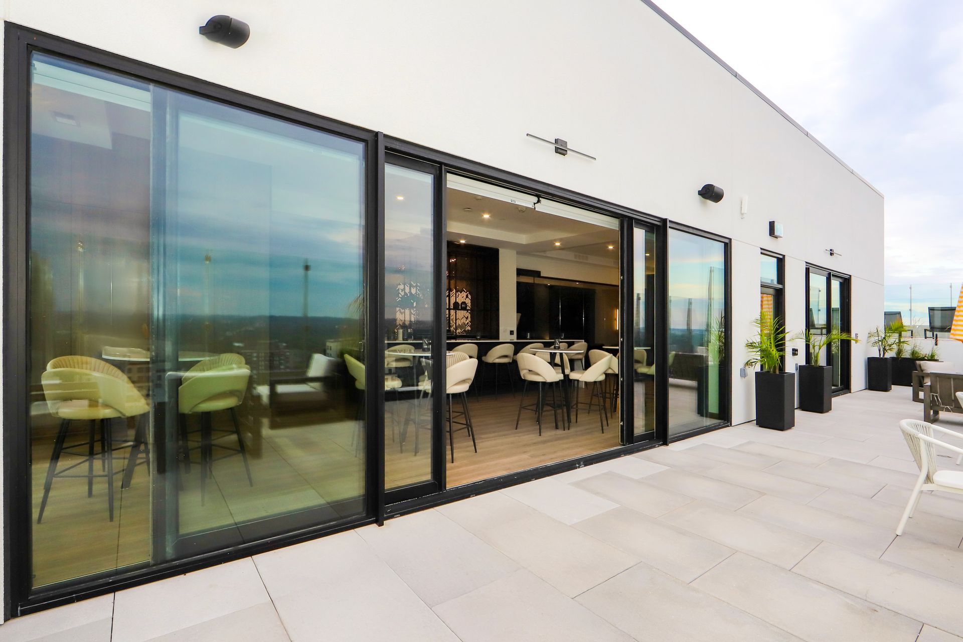 Rooftop bar with sliding glass doors, a stone patio, and cityscape view.
