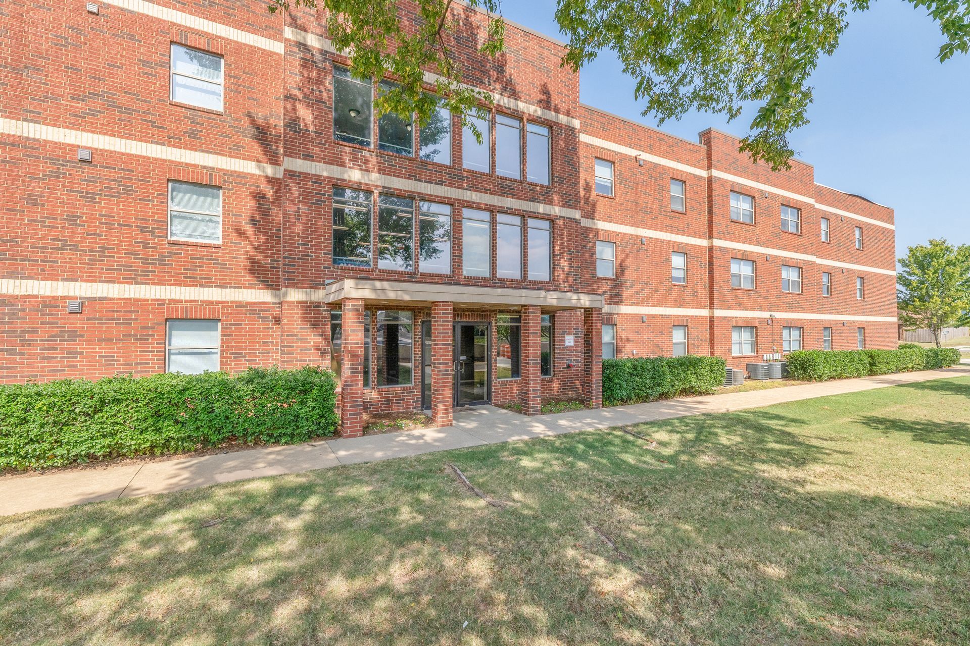 A large brick building with a lot of windows and a walkway in front of it.